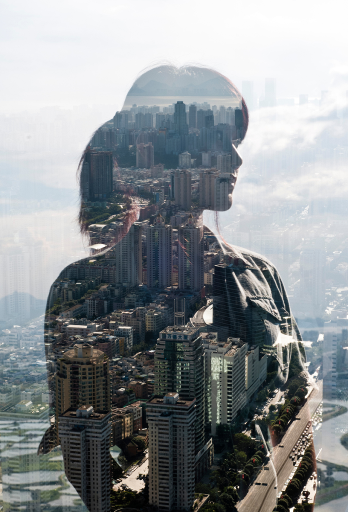 Nő sziluettje felhőkarcoló ablakán, rajta keresztül látszik a városkép