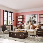 Stílusosan berendezett nappali rózsaszín fallal, régi utazóláda a bézs kanapé előtt, bőr függőfotel