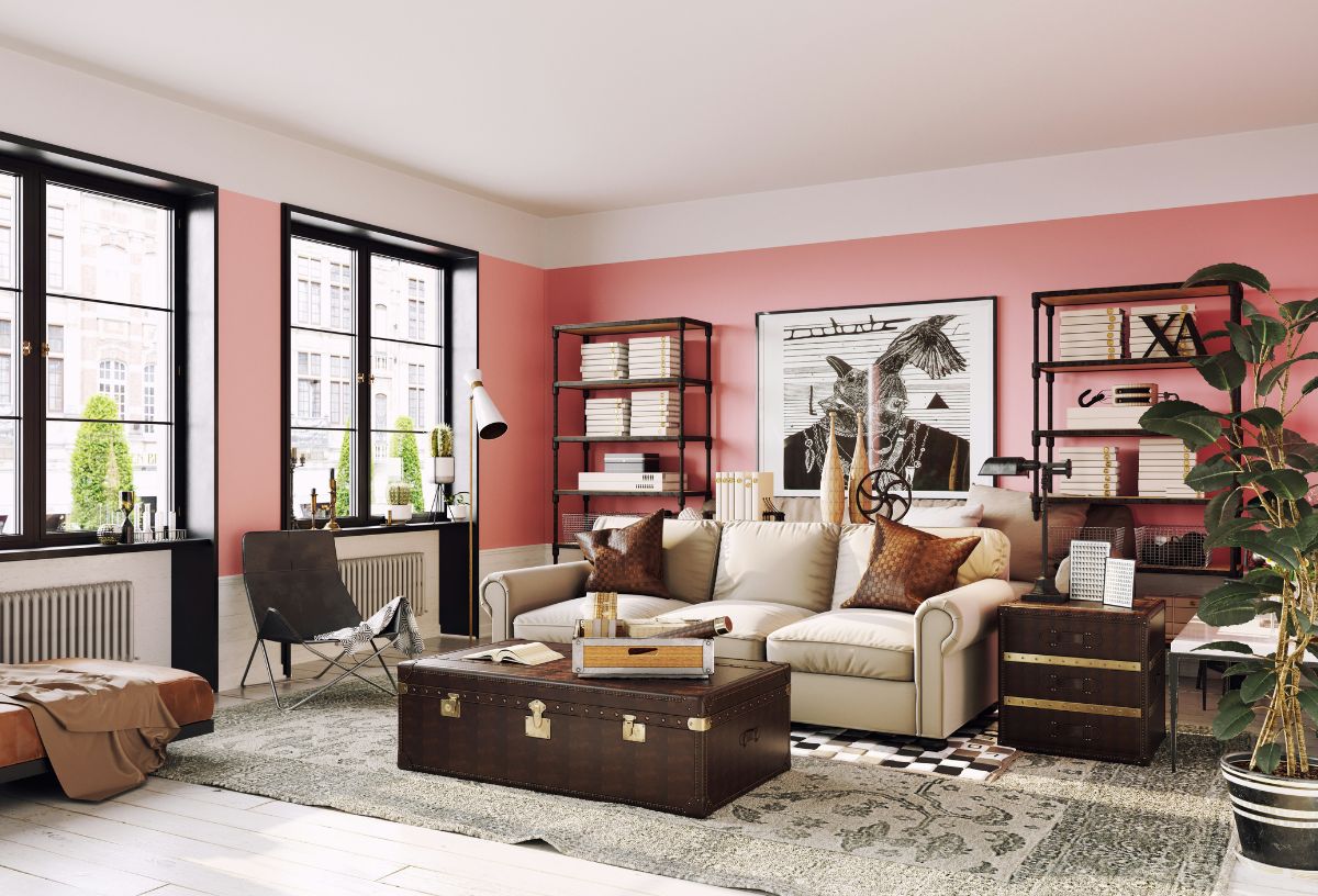 Stílusosan berendezett nappali rózsaszín fallal, régi utazóláda a bézs kanapé előtt, bőr függőfotel