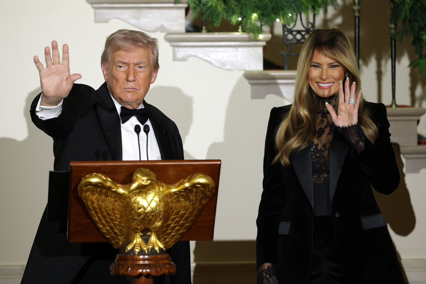 Donald Trump amerikai elnök (balra) és Melania Trump first lady (jobbra) integetnek a résztvevőknek a Fehér Ház előcsarnokában tartott kongresszusi bálon 2025. december 11-én Washingtonban.