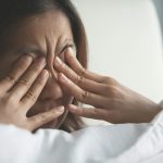 Fiatal nő fáradt szemeit dörzsöli