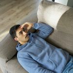 Bosszús fiatal férfi fekszik a kanapén, fogja a fejét