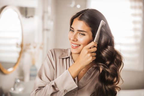 Fiatal nő fésülködik a tükör előtt