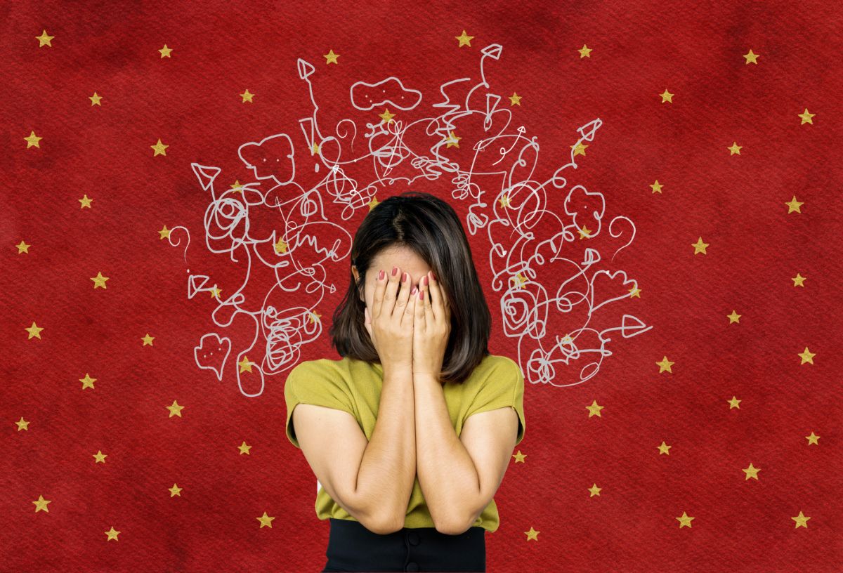 Egy nő fogja fejét, ki van borulva, piros csillagos háttér előtt