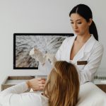 fehér köpenyes doktornő női páciens mellett áll