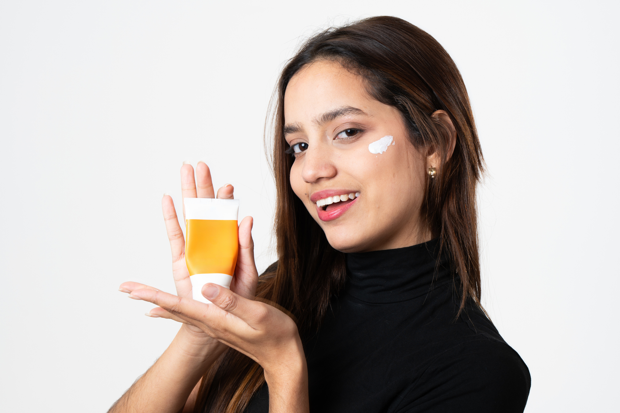 fiatal nő egy arckrémet mutat tubusban