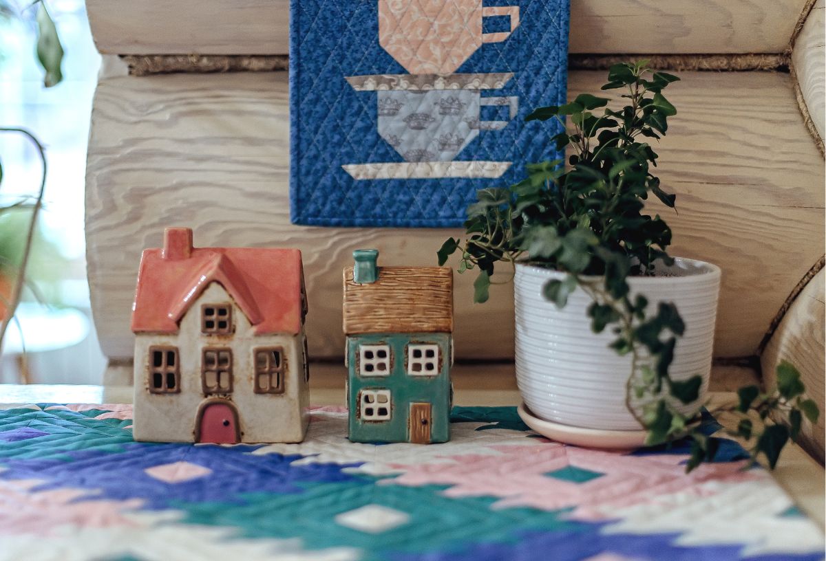 Patchwork takarón két kerámia ház, fehér cserépben szobanövény fa felületen