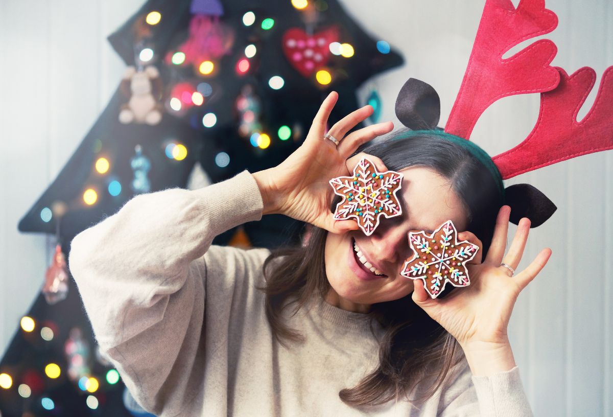 Nő mézeskalácsokat tart a szeme elég, szarvasagancs fejpántban bolondozik a karácsonyfa előtt