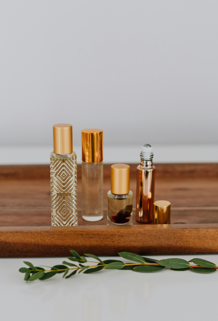 Különféle parfümök és illóolajok egymás mellett fa tálcán különböző alakú üvegekben