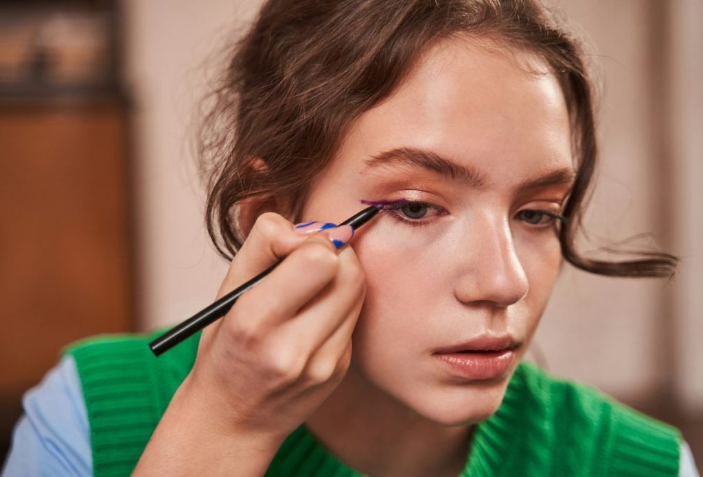 Tinédzser lány szemceruzával sminkel