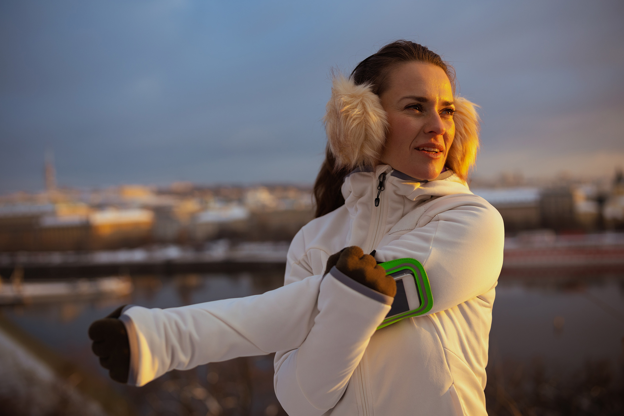 Fiatal nő fülmelegítőben nyújtja a karját