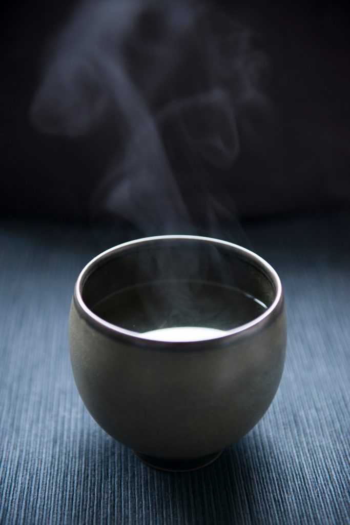 Egy fekete teáscsésze, amiben gőzölög a tea