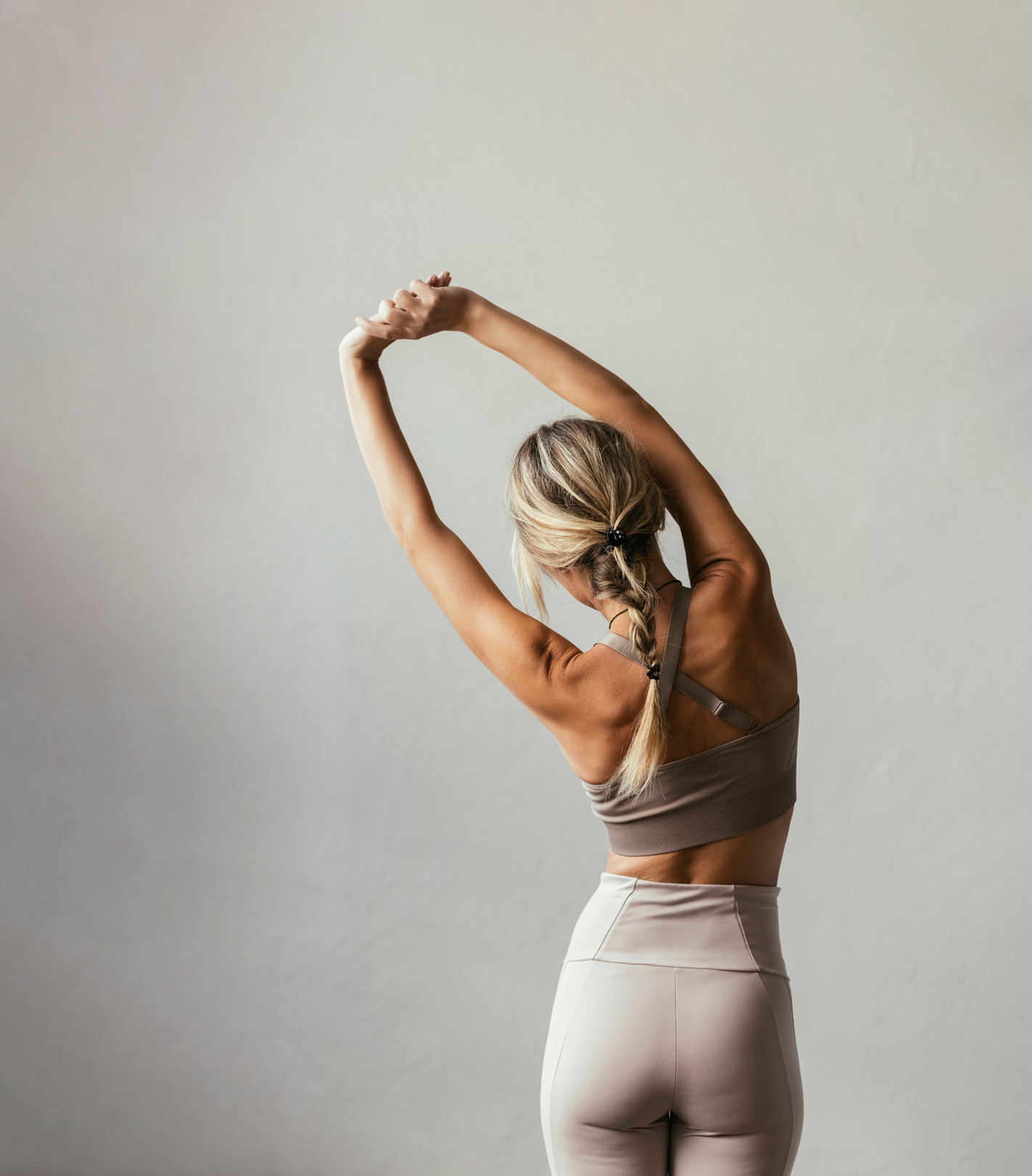 Egy fiatal szőke nő, aki hátulról nyújtózkodik