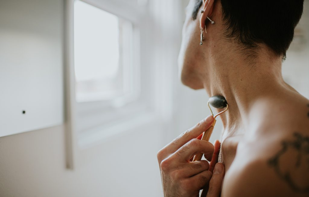 Fiatal férfi jade rollerrel masszírozza az arcát