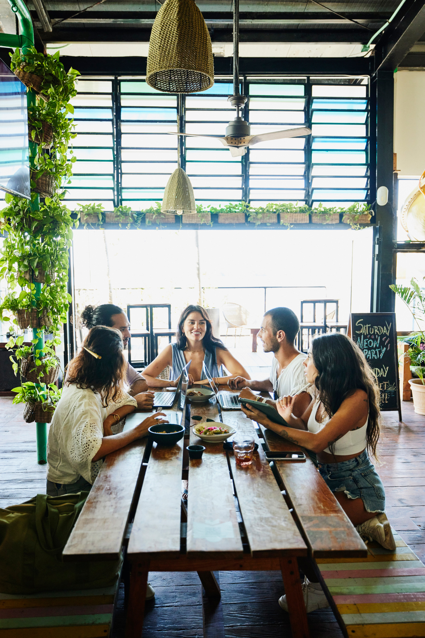 Férfiak és nők az asztalnál ülnek és mosolyogva beszélgetnek