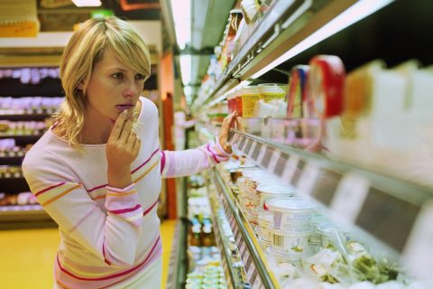 egy nő vásárol, nézelődik a boltban a polcok között