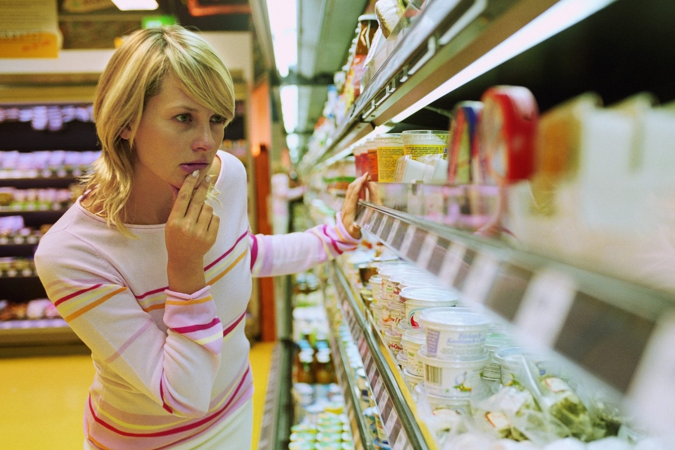 egy nő vásárol, nézelődik a boltban a polcok között