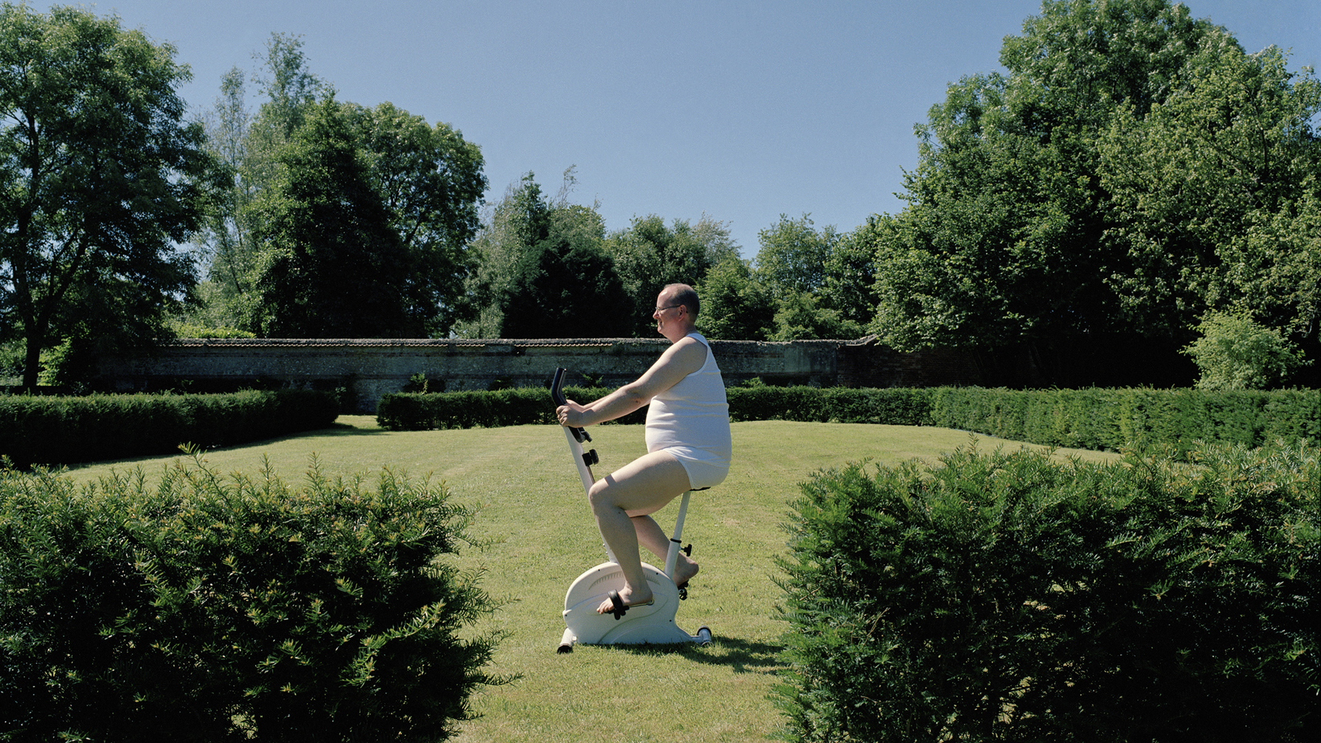 Túlsúlyos férfi egy szobabiciklin a természetben