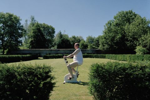 Túlsúlyos férfi egy szobabiciklin a természetben