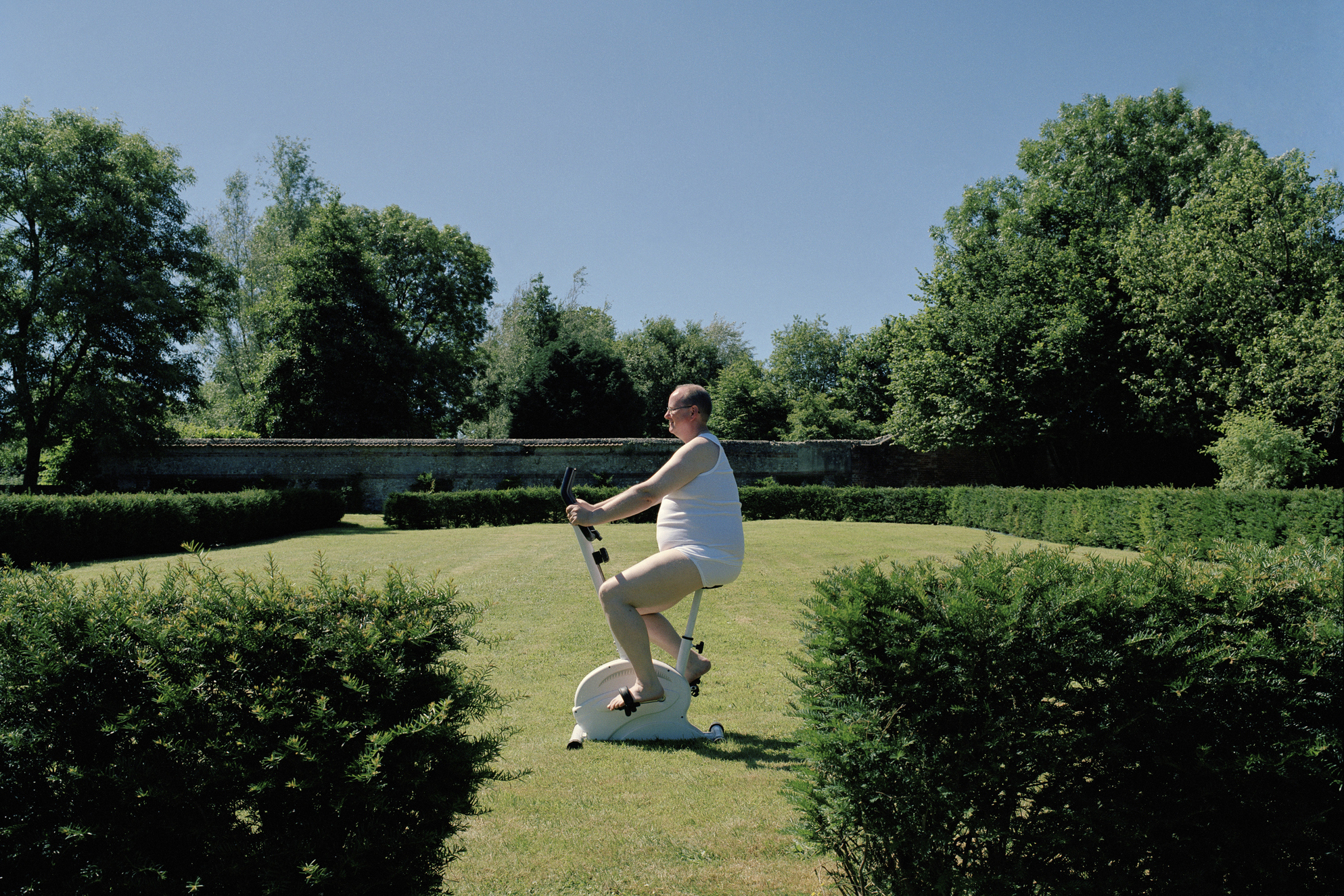 Túlsúlyos férfi egy szobabiciklin a természetben