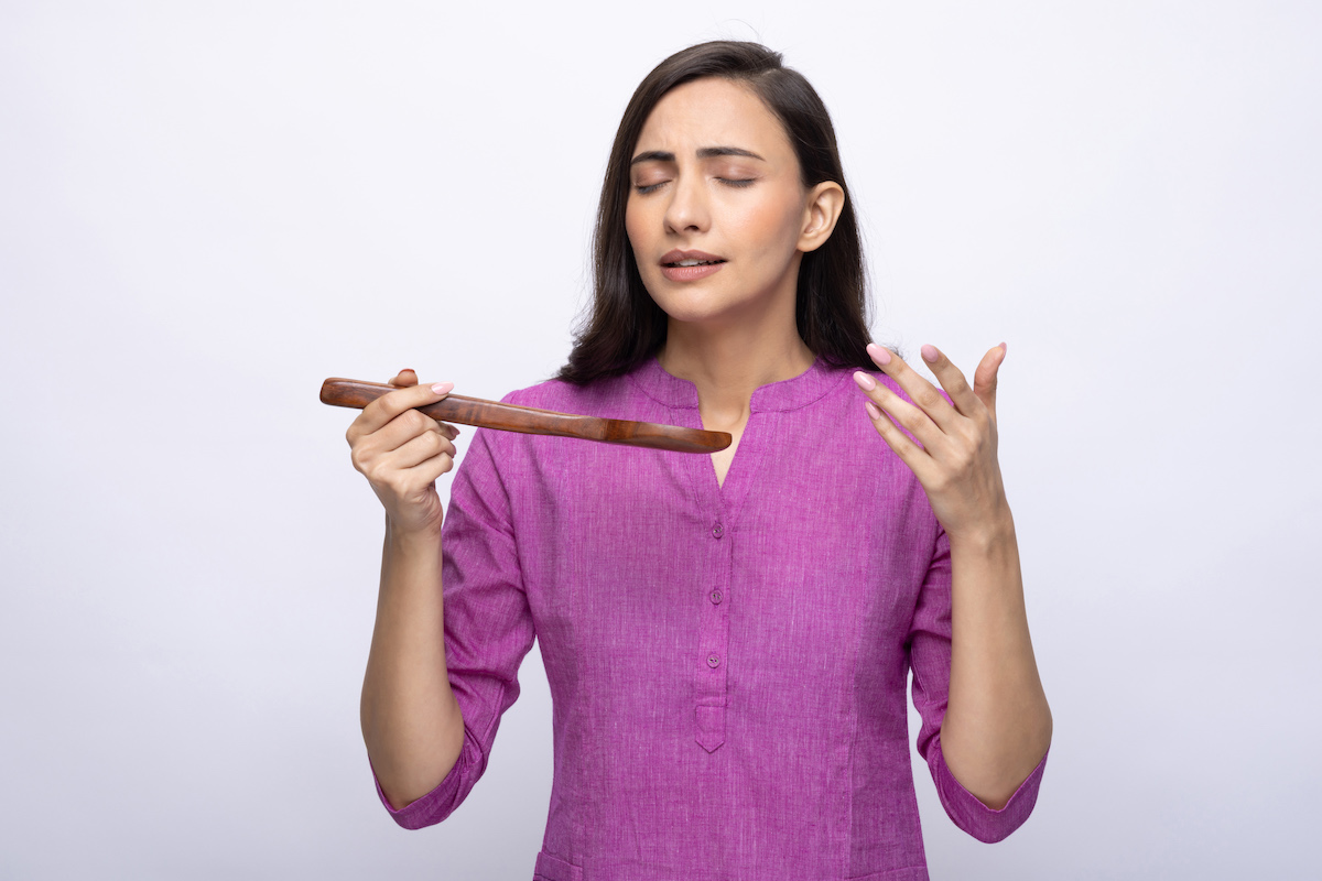 lila pólós nő kezében fakanállal behunyt szemmel