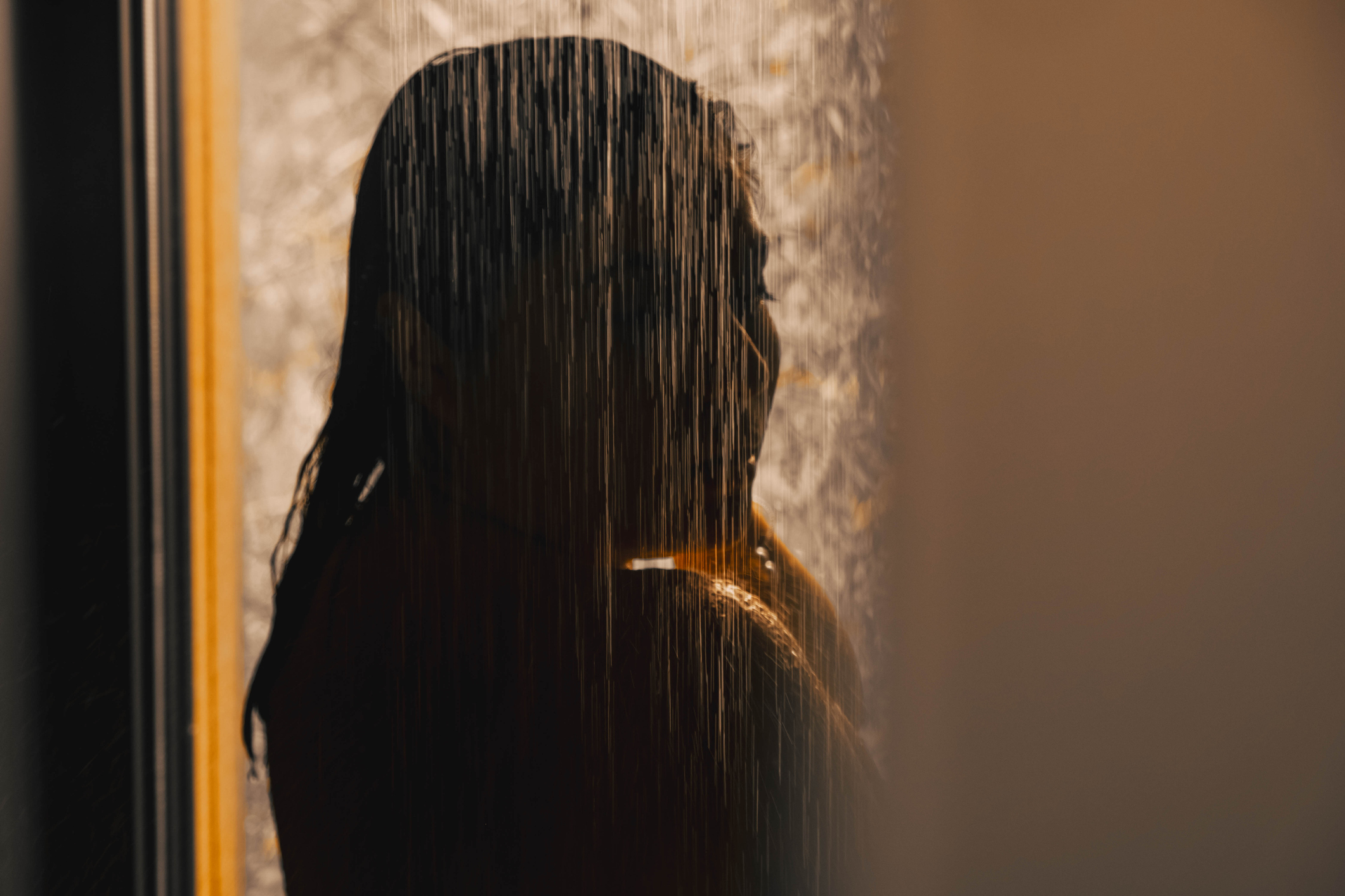 sotetben-zuhanyzas-ez-a-rituale-segit-ellazulni | Marie Claire hosszú hajú nő sziluettje, aki félhomályban zuhanyozik