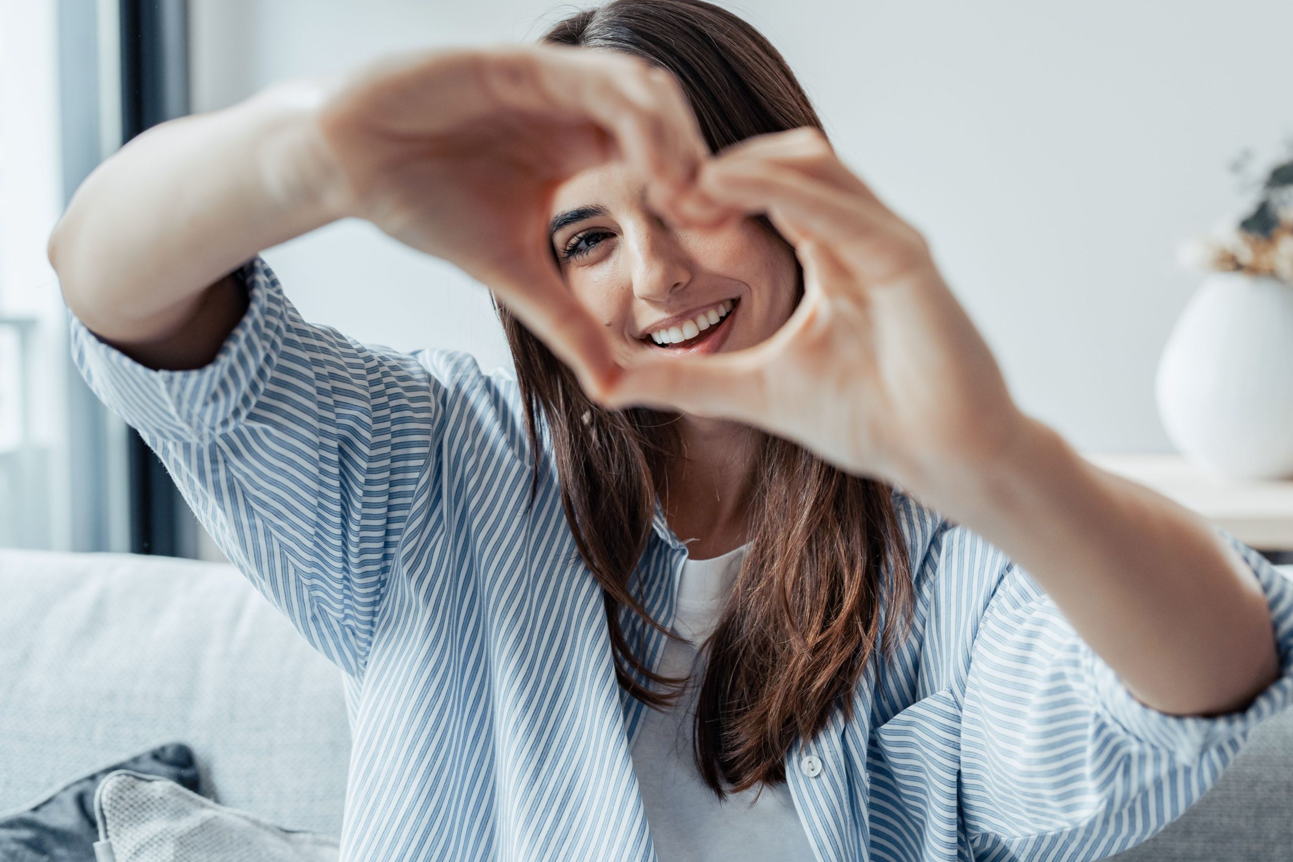 Boldog nő szívet mutat a kezével