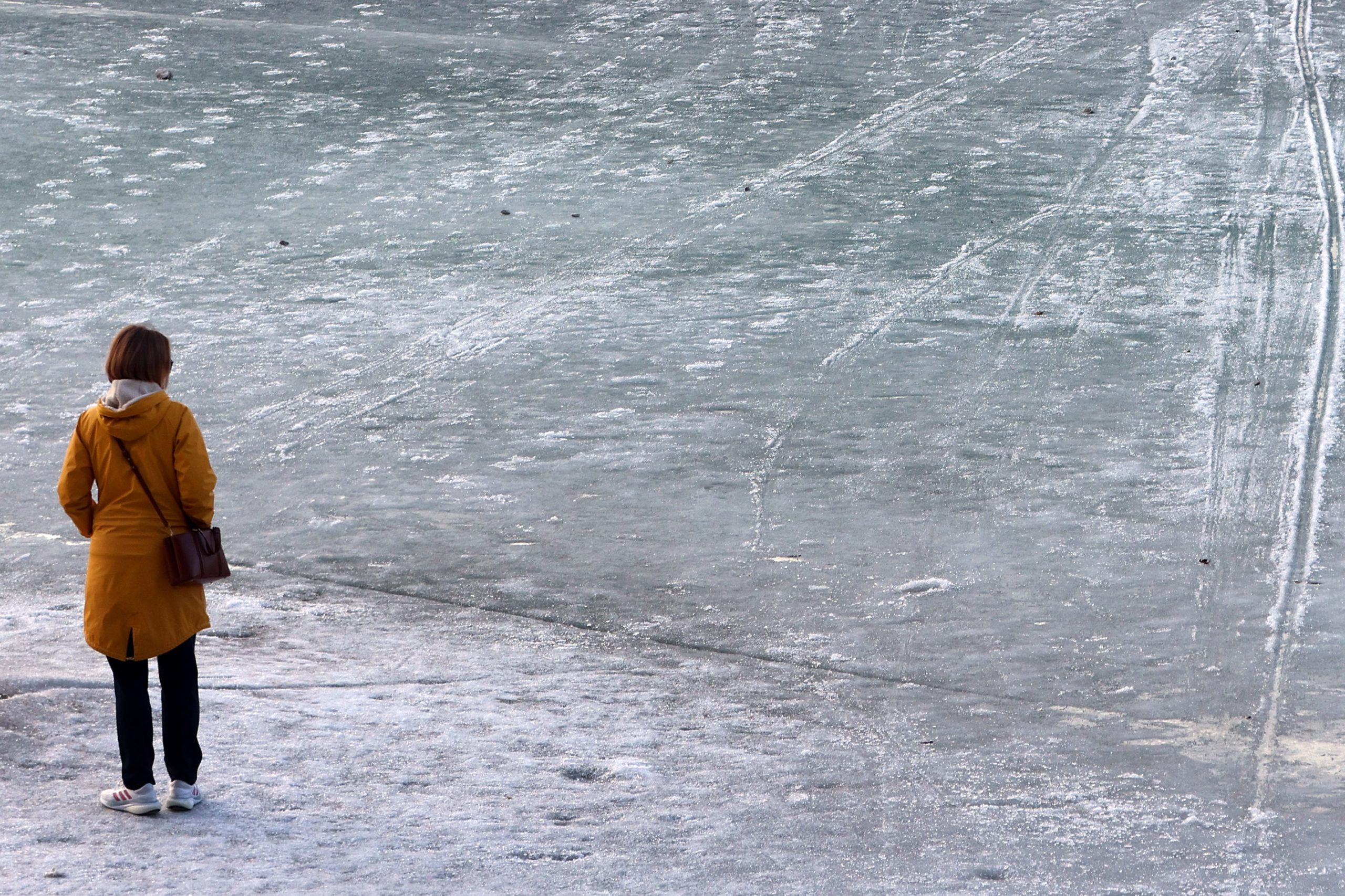 Nő nézi a befagyott tavat
