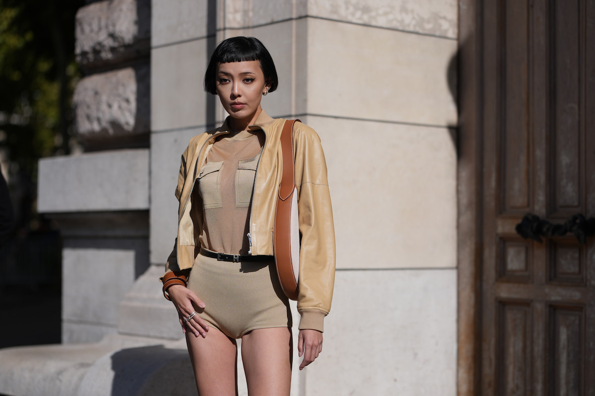 frufrutrend-2026-5-divatos-fazon-hajvagashoz | Marie Claire Kiwi Lee Han rövid, egyenes fekete bob frizurát visel tompa mikrofrufruval; ezüst karika- és stekker fülbevalókat; barna bőr válltáskát krémszínű vászon betéttel és széles bőrpánttal; világosbarna, rövidített bőr bomberdzsekit; világosbarna, hálós anyagú, álgarbós felsőt zsebekkel, betűrve; valamint világosbarna, texturált, magas derekú rövidnadrágot, amelyet egy vékony fekete öv rögzít. Hermès, Párizsi Divathét, 2025.