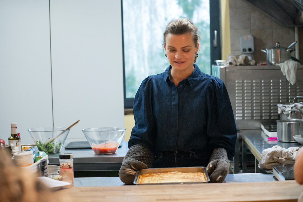 női séf ételeket készít el a konyhában, sütőkesztyűt visel