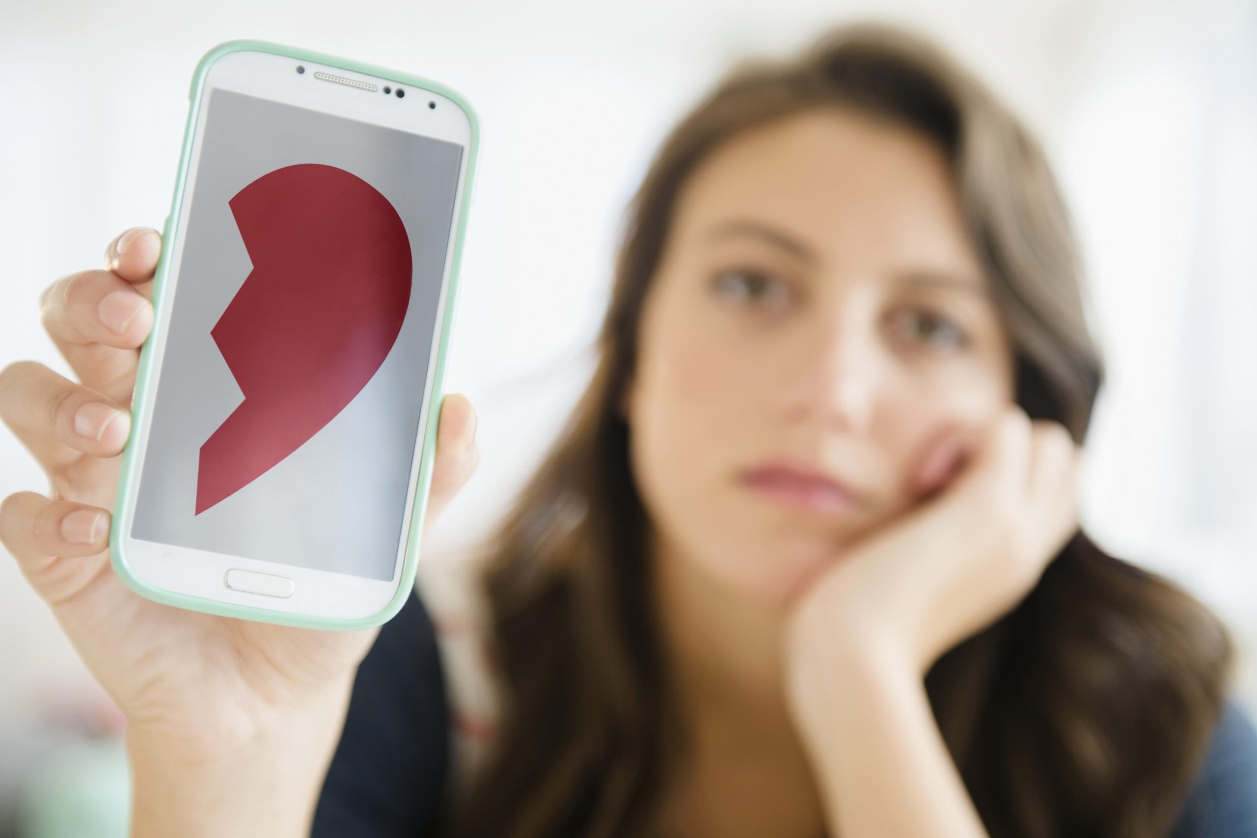 Egy szomorú nő telefont fog a kezébe