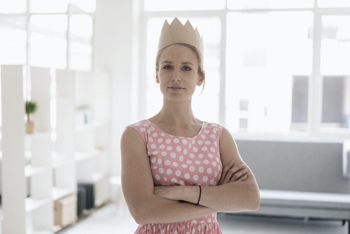 Rózsaszín ruhás nő karbatett kézzel, koronával