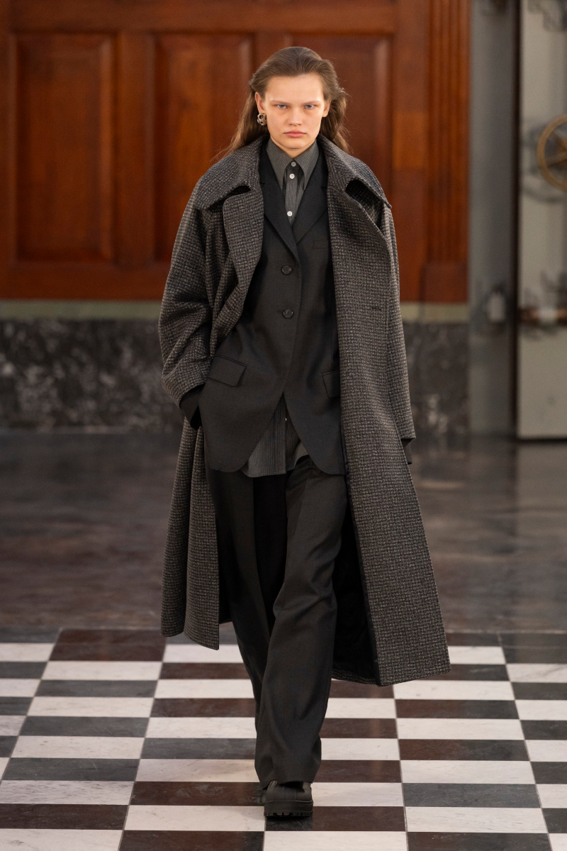 Barna hajú modell az MKDT 2026-os őszi–téli bemutatóján sötét szövetkabátban, öltönyben