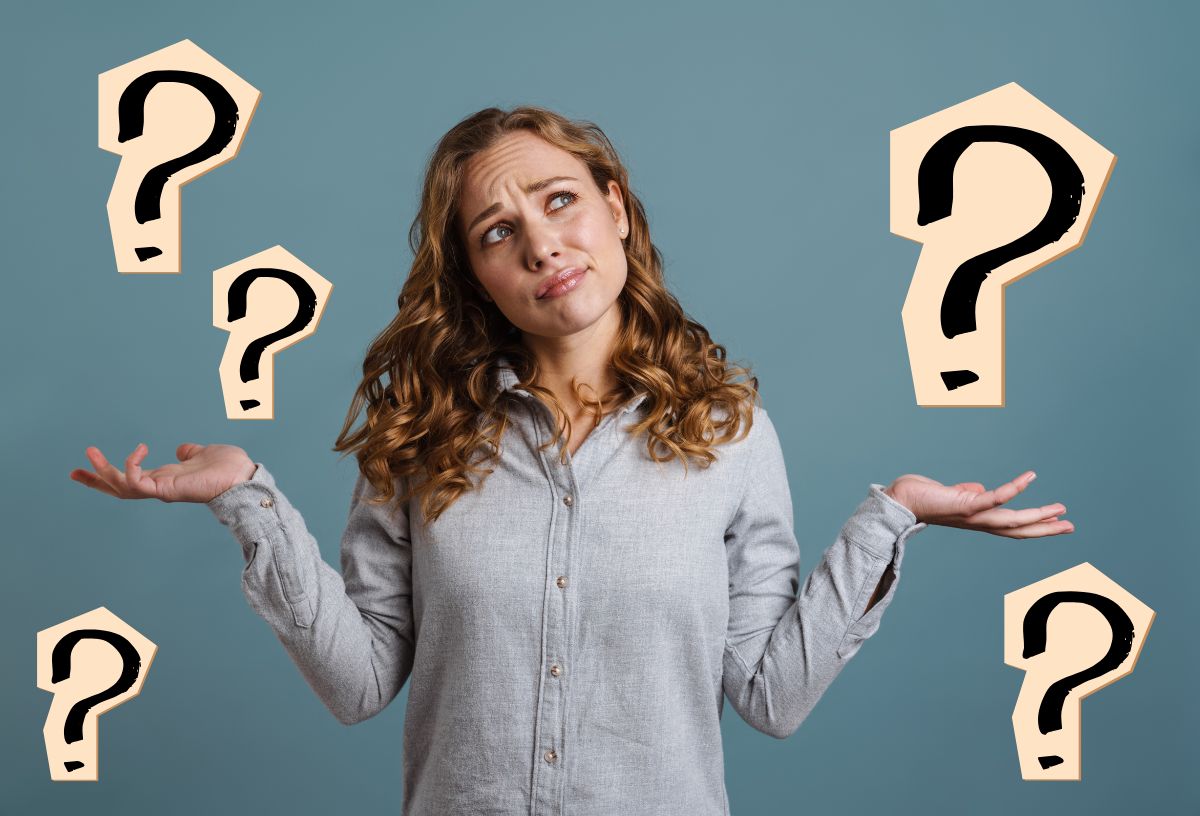 Szép fiatal nő szürke ingben széttárt karral, fejét oldalra billetnve, kérdőn néz, körülötte kérdőjelek barackszínű háttérrel, szürkészöld fal előtt