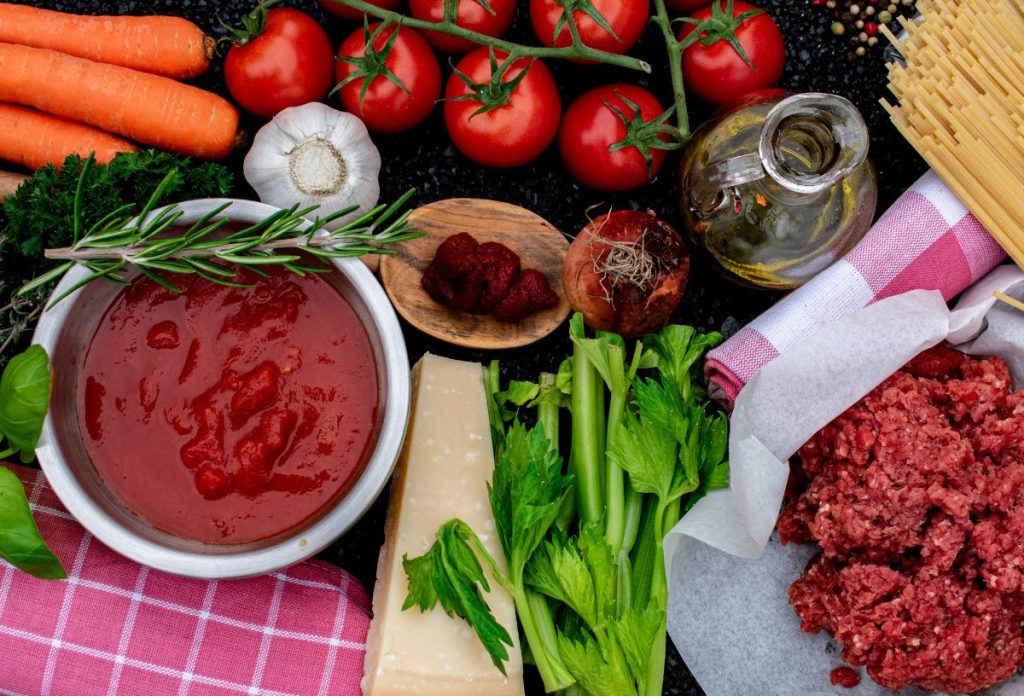 Bolognai szósz hozzávalók: répa, paradicsom, fokhagyma, szárzeller, darálthús egy asztalon