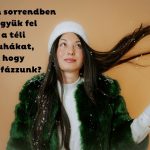 Karamell színű háttér, szép fiatal, sötét hajú nő fehér sapkában, zöld műszőrme bundában dobja hátra a haját, fehér kesztyűs kezét felemeli