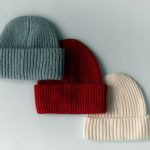 Kék, piros és fehér téli kötött sapka sréhen, kis átfedéssel fehér felületre fektetve