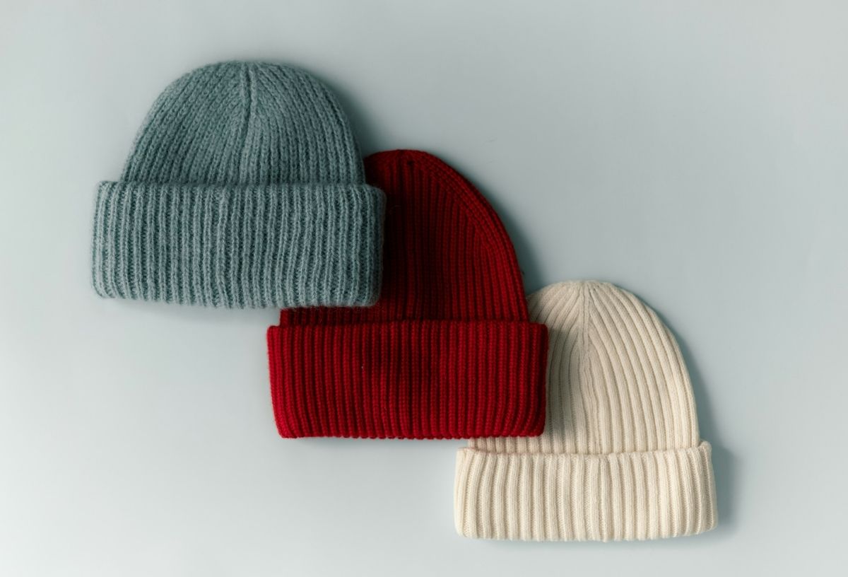 Kék, piros és fehér téli kötött sapka sréhen, kis átfedéssel fehér felületre fektetve