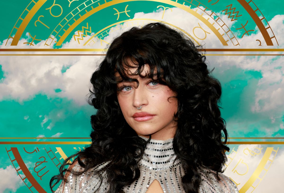 Barna hajú színésznő a Critics Choice Awards 2026-os díjátadón ezüst garbós ruhában, orrkarikával, mögötte arany asztrológiai kör és türkiz égbolt