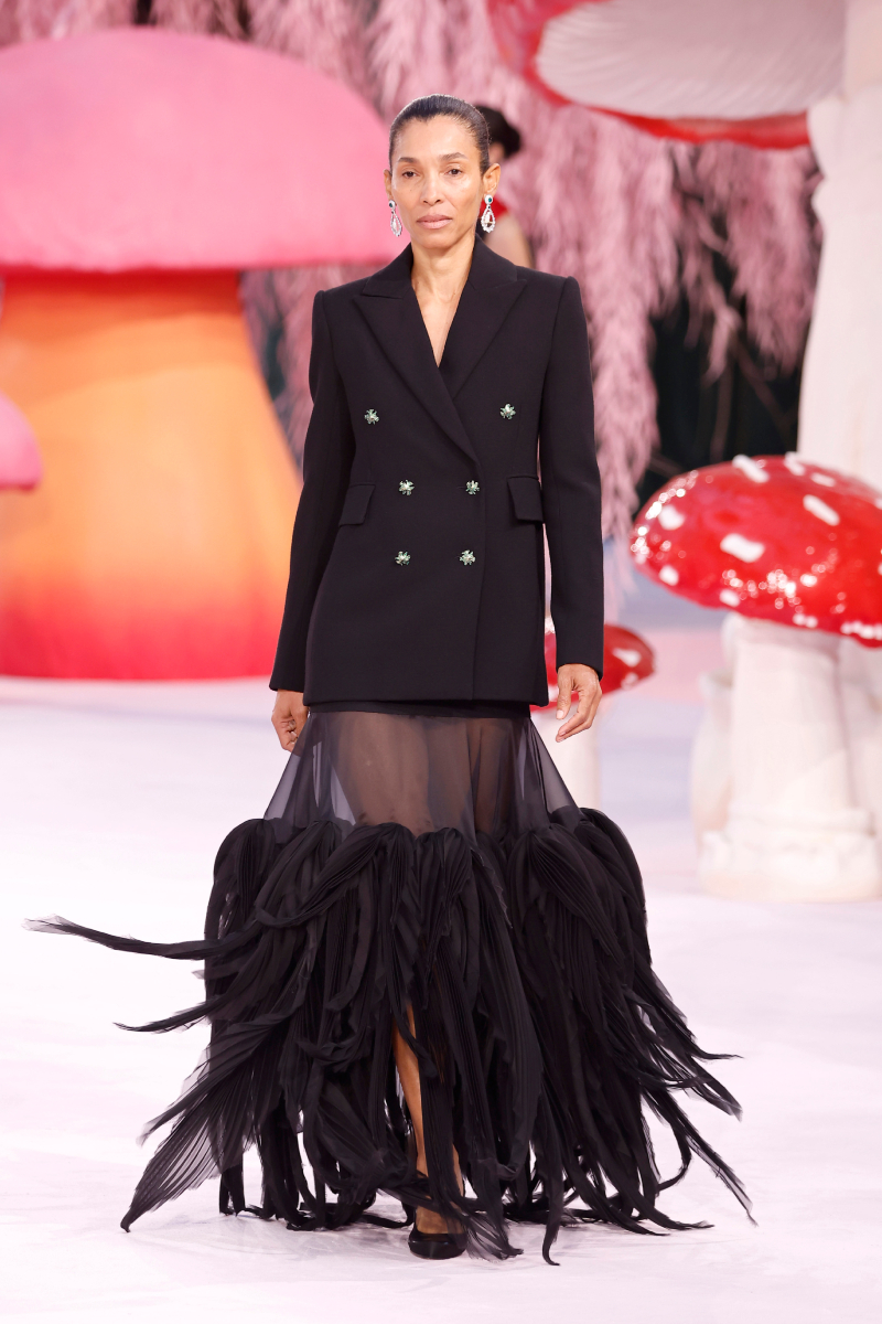 Barna hajú modell a Chanel 2026-os tavaszi–nyári haute couture kollekciójának kifutóján fekete blézerben, áttetsző fekete szoknyában