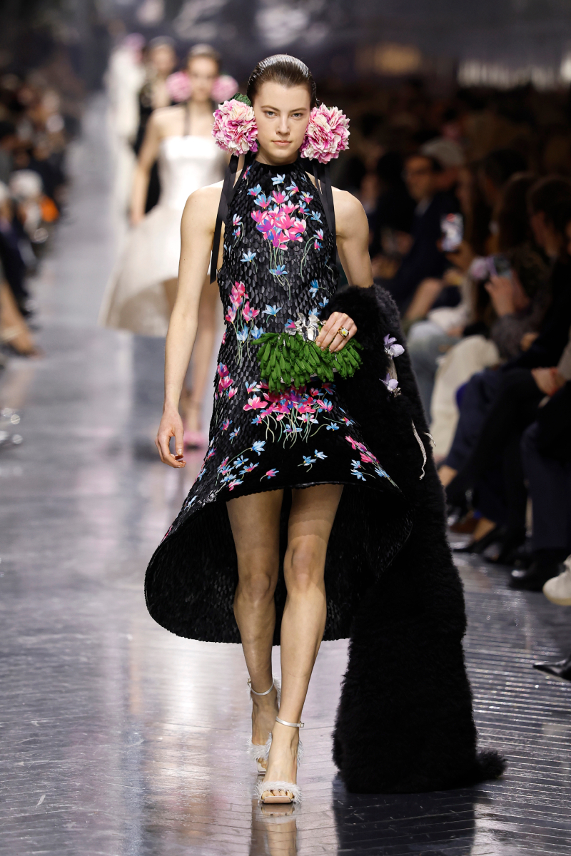 Barna hajú modell a Christian Dior 2026-os tavaszi–nyári haute couture bemutatóján virágmintás ruhában, fűzöld kistáskával