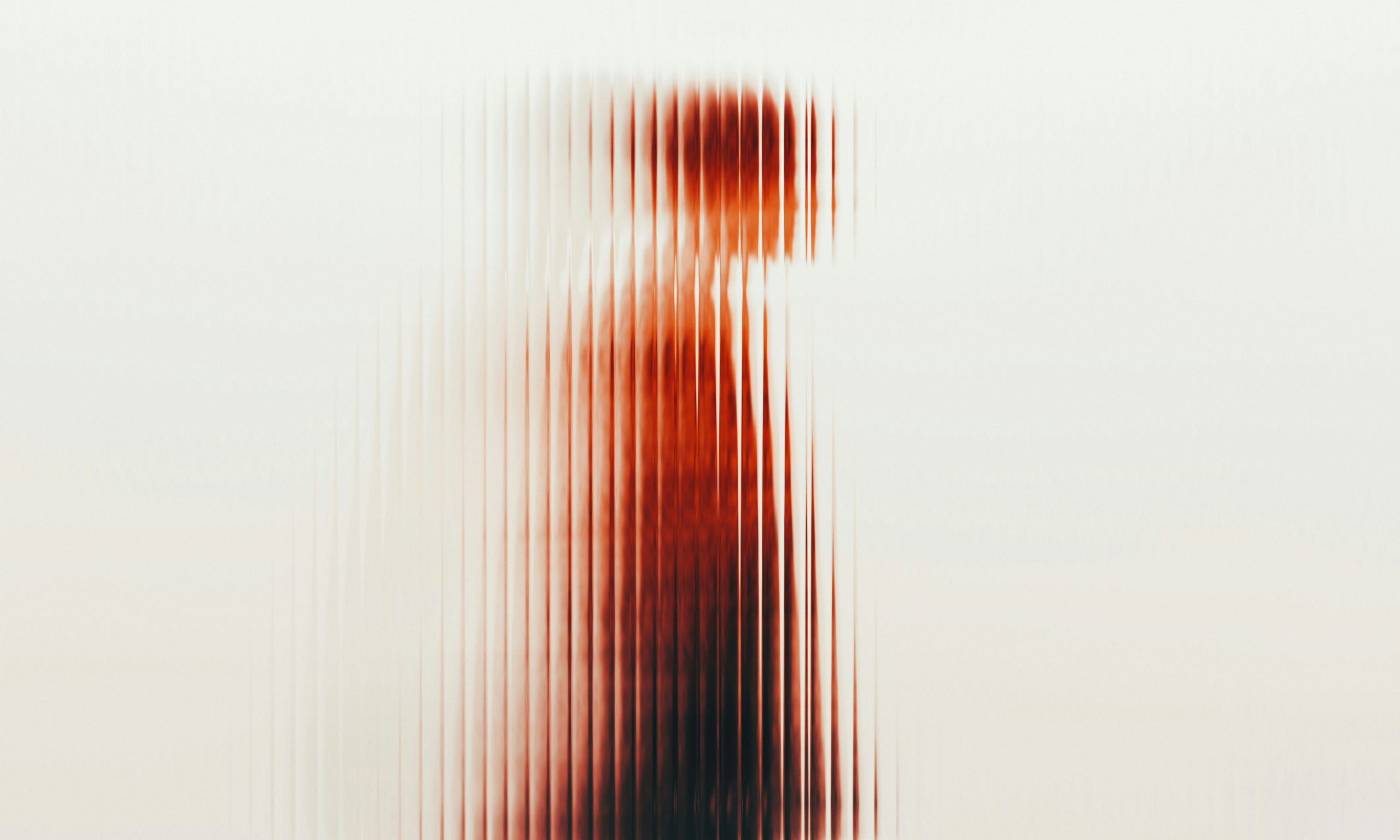 Elmosódott alak sziluettje egy bordázott üvegfal mögött