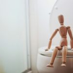 Fa figura ül egy vécé peremén