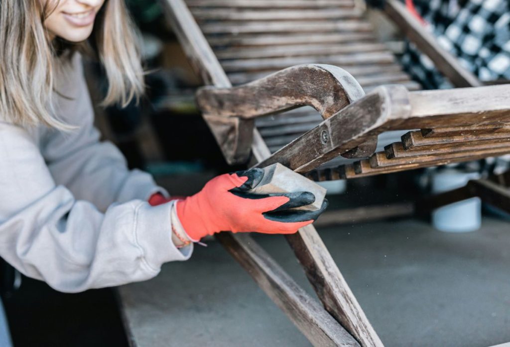 legjobb-hobbi-butor-restauralas | Marie Claire Nő piros munkavédelmi kesztyűben régi fa hintaszéket csiszol