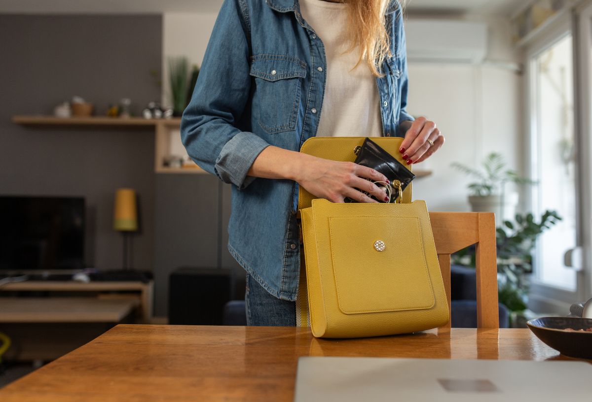 Farmeringes nő asztal mellett állva sárga kistáskábal pakol és rendszerez