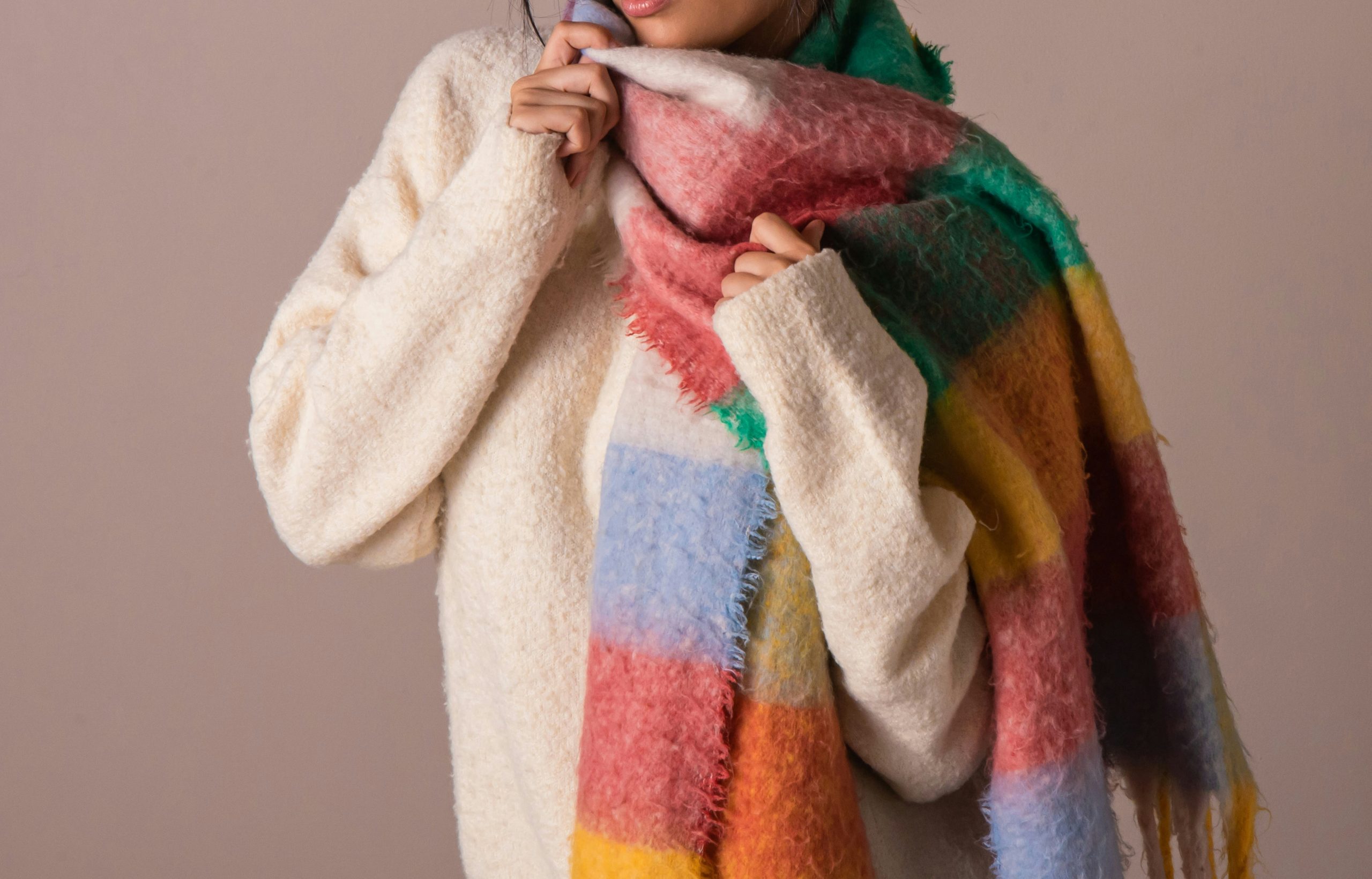 Fiatal nő vastag pulóverben és csíkos sálban