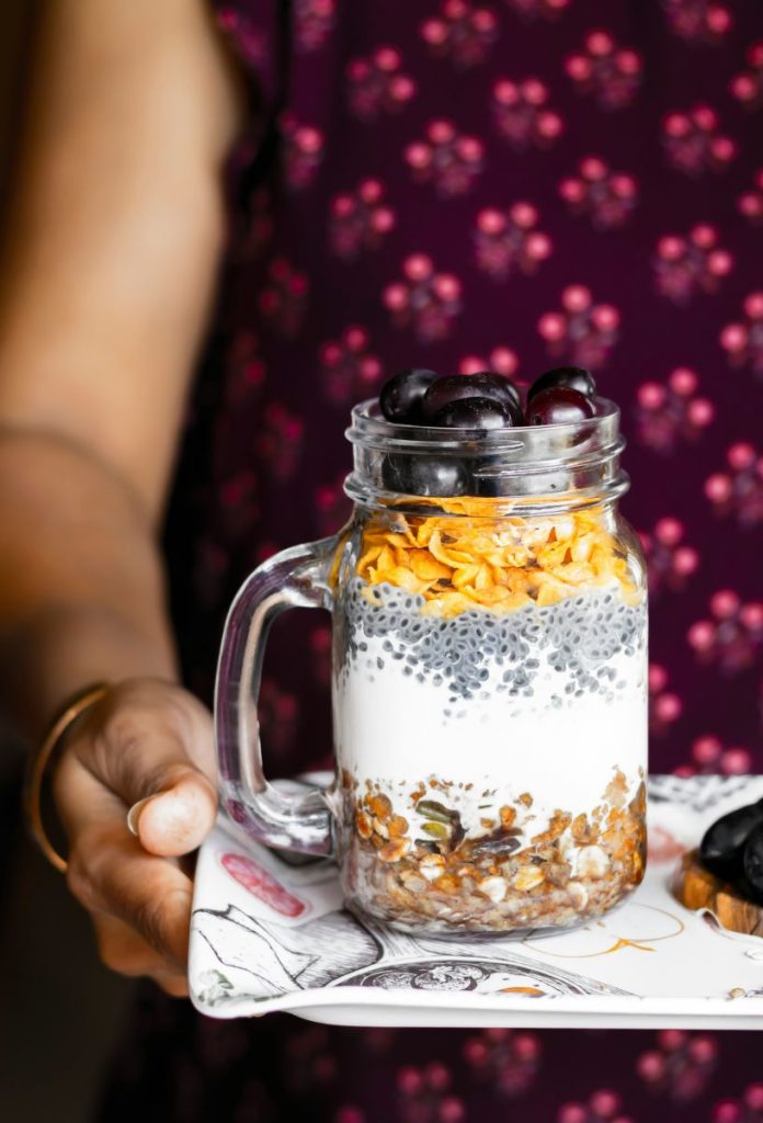 seed-cycle-magok-hormonok | Marie Claire Nő tálcán üvegbe rétegezett granolát, olajos magokat, görög joghurtot visz