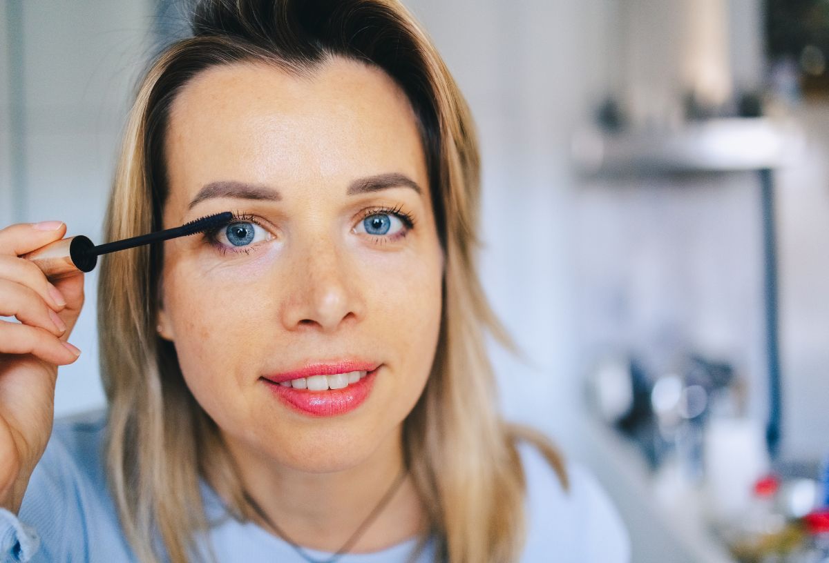 Fiatal, szőke hajú, kék szemű nő szempillaspirált visz fel