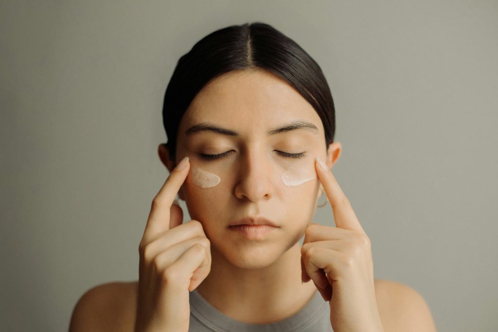 Nő csukott szemmel, szemkrönyékápolót ken a szeme alá