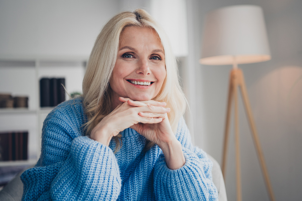 Csinos idős nő mosolyog egy modern lakásban